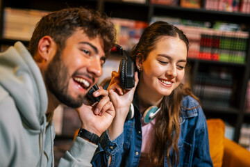 Young students sharing headphones in library cafe
