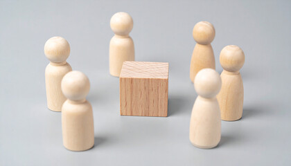 Wooden human figures surrounding small wooden cube, teamwork metaphor. Community