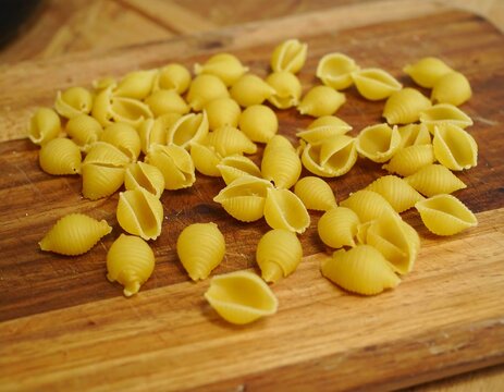 Small pasta shells on a wooden cutting board