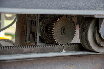 Gear and belt systems of an industrial machine are clearly visible, highlighting their intricate design and function in motion under natural light