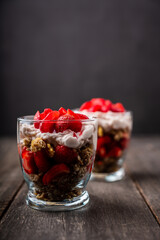 Greek yogurt, granola and strawberry on the rustic background. Selective focus.