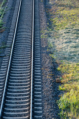 close-up of a straight railway track with a meadow next to it