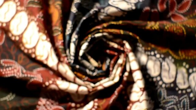 Close-up view of intricately patterned batik fabric, rolled and spiraled.