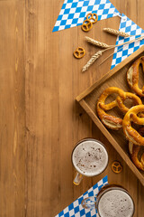 Celebrating Oktoberfest with fresh pretzels, beer mugs, vertical flatlay top view wooden background, and blue checkered patterns