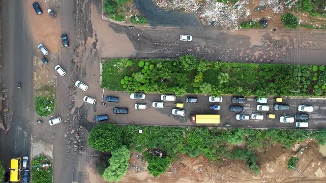 aerial drone shot showing flooding and broken roads with water filled potholes at a busy intersection leading to traffic congestion jams due to poor road quality and heavy rains