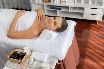 Obraz premium Caucasian woman customer enjoying relaxing anti-stress spa massage and pampering with beauty skin recreation leisure in day light ambient salon spa at luxury resort or hotel. Quiescent