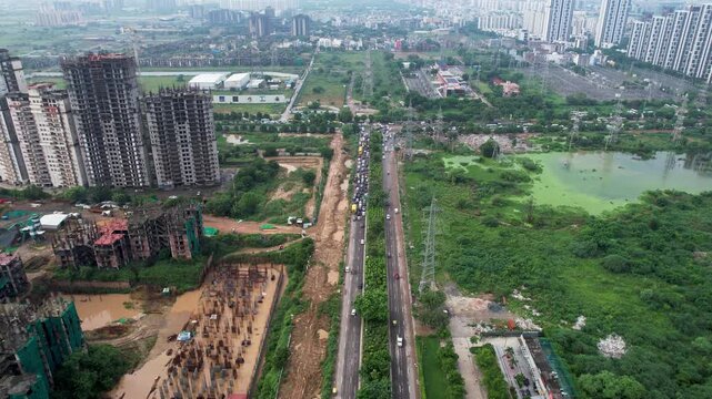 Aerial drone shot forward and descending over traffic jam at busy intersection owing to flooded and damaged roads during monsoon due to poor quality and bad maintenance in Gurgaon, Delhi, Noida