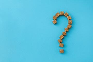 Question mark made of cane sugar pieces. Concept of healthy nutrition and harm of eating sweets. Selective focus, copy space