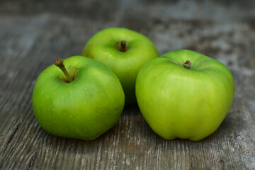 Tree green fresh apples on rustic wooden table. Natural background. Health food concept.