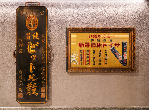 osaka, umeda - dec 12 2024: Japanese Showa-era retro wooden signs and framed advertisement for durable shoji paper and stomach medicine photographed in the Takimi Koji alley of Umeda Sky Building.