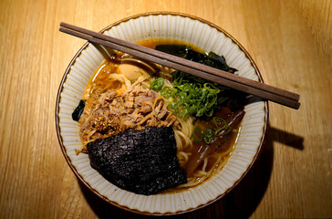 Steaming ramen bowl with tender pork, fresh scallions, seaweed, and rich broth, served under warm light, capturing comfort, flavor, and the art of traditional cuisine.