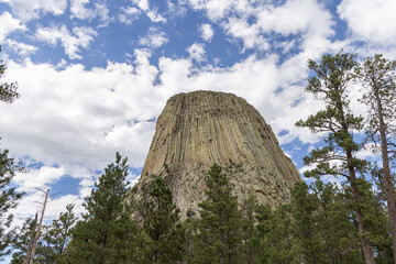 Devils Tower National Monument blue sky white clouds trees