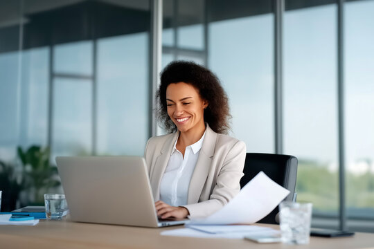 Smiling businesswoman working on laptop in modern office