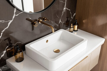 Fototapeta premium Modern bathroom interior with white rectangular sink, gold faucet and marble wall design concept on wooden vanity top in elegant minimalist style. Ai generative