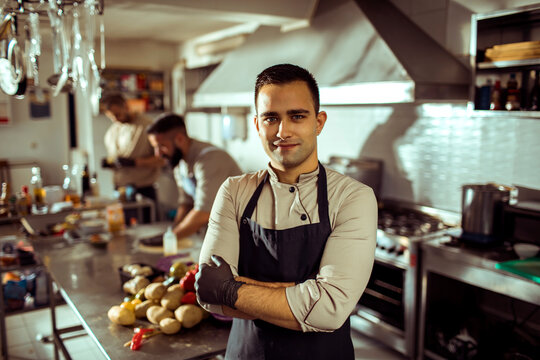 Smiling young chef standing confidently in gourmet restaurant kitchen