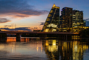 Dramatic sunset with illuminated city office blocks reflected in the golden waters of Lady Bird lake in Austin Texas