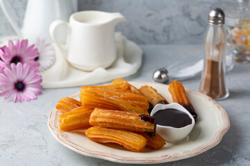 Traditional Spanish treat street fast food churros on a plate with hot chocolate sauce.