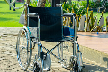Fototapeta premium Empty Silver Wheelchair on Stone Path in Green Park