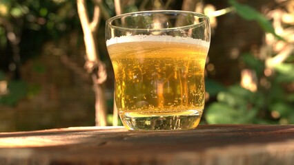 A glass of beer on the table. A glass of beer on a wooden table. A beer glass outdoors
