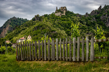 Image of an old wooden fence in the foreground with a castle high up a hill in the background.