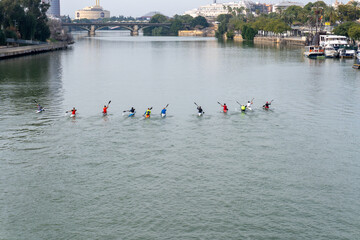 River kayak race in Seville, Spain: A vibrant photograph captures a kayak race, with individuals paddling down the river against a city backdrop, emphasizing strength, competition, and the human spiri
