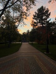 Walking in the old autumn city park at sunset