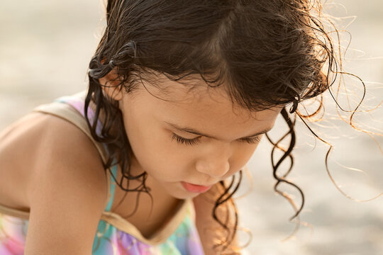 Closeup portrait of child girl on sandy beach at sunset time, childhood memories and family vacation concept