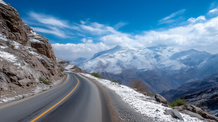 Scenic mountain road winding towards snow-capped peaks on a sunny day