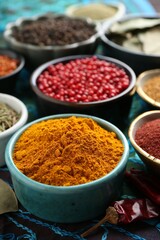 Different aromatic spices on blue tablecloth, closeup