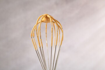 Making delicious dalgona coffee. Whisk with cream on blurred background, closeup
