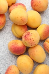 Many fresh apricots on grey textured table, flat lay