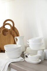 Different clean white dishware and wooden cutting boards on counter in kitchen
