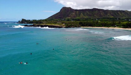 Obraz premium Turquoise water with surfers and a mountain backdrop.