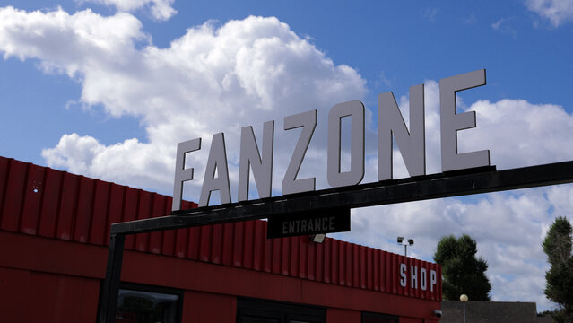 LONDON, UK - AUGUST 5, 2025 - Large fanzone sign above entrance of red venue welcoming fans under partially cloudy sky