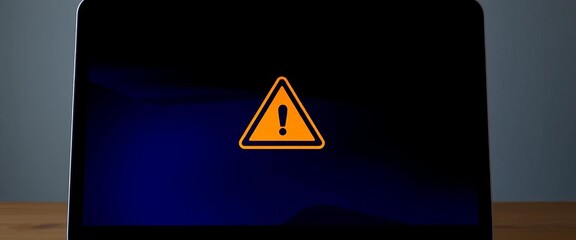 Laptop screen displays triangle warning sign, signifying system error or maintenance,  priority,  technology