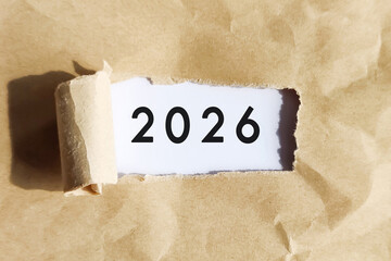 Year 2026 revealed under torn brown paper, representing new beginnings, goals, and future vision