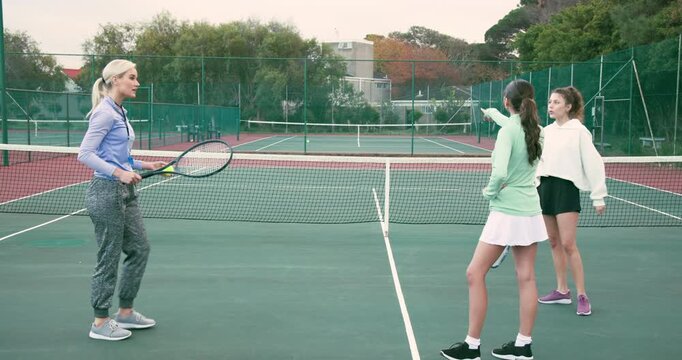Female coach feeding ball, demonstrating forehand and correcting swings on tennis court, copy space