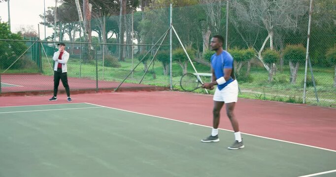 Following coach woman and African American tennis players practicing forehands on court, copy space