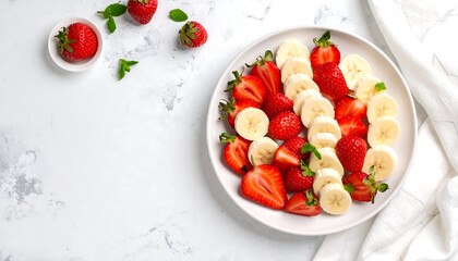 Freshly sliced strawberries and bananas on a white plate.