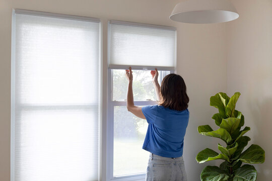 Woman closing window shades