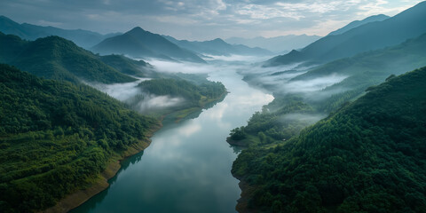 Fog covering river flowing through green mountains at dawn