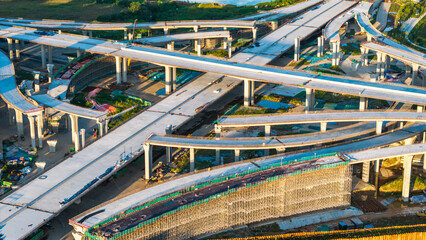 Naklejka premium Aerial perspective showcasing a complex multi-layered highway interchange with interconnected elevated structures and ramps.