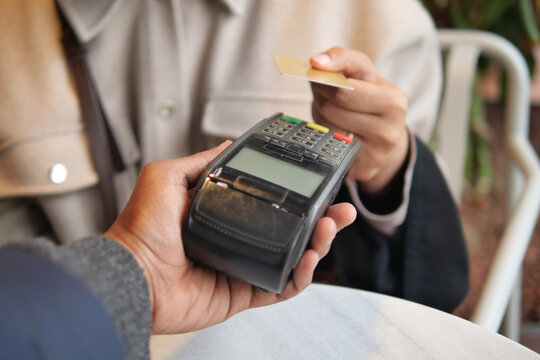 Customer makes payment using card at cafe in urban setting