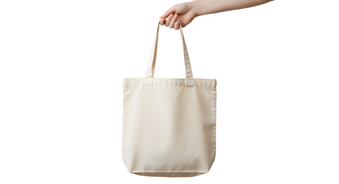 Hand holding a beige reusable tote bag with long handles isolated on transparent background.