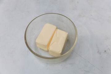 Half sticks of butter in a glass dish on marble countertop