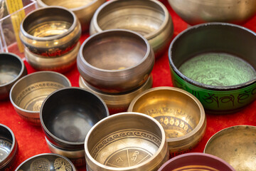 Collection of Tibetan singing bowls with engraved designs displayed on red cloth.