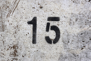 The number 15 stencilled in black on a weathered concrete surface