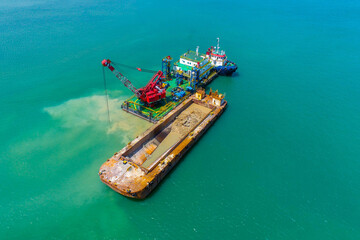 Industrial dredging barge in offshore construction project with tugboat support