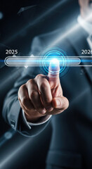 Obraz premium Businessman hand touching futuristic digital interface, progress bar moving from 2025 to 2026, technology innovation, future concept, glowing blue light, modern suit, abstract background