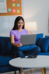 Naklejka premium Asian Freelancer Working From Home Using Laptop on Sofa